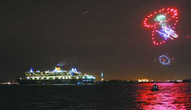 Cruise ship at night with fireworks overhead.