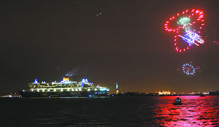 Cruise ship at night with fireworks overhead.