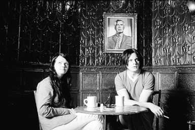 Black and white image of Meg White and Jack White sitting at a small table.