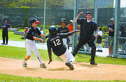 A baseball player slides into a base while others watch during a game.