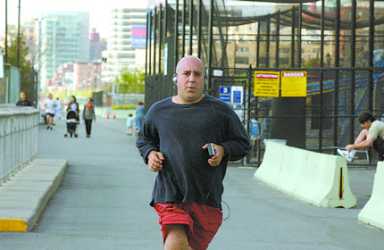 Bald man in black shirt and red shorts jogs on a path.