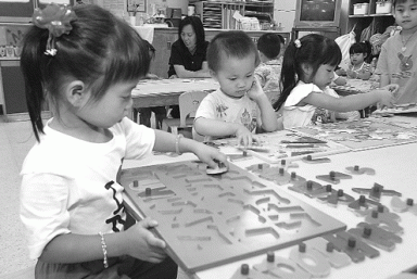Young children in a classroom setting playing with educational puzzles.