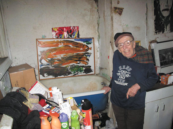 Photos by Clayton PattersonTaylor Mead, 87, displaying one of his paintings, hung above his bathtub in his cluttered Ludlow St. apartment.