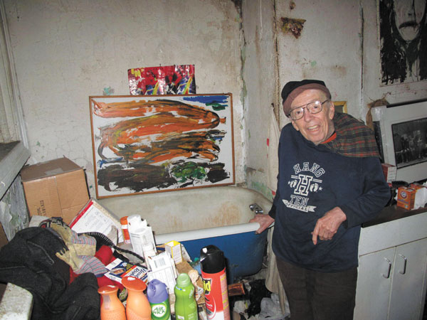 Photos by Clayton PattersonTaylor Mead, 87, displaying one of his paintings, hung above his bathtub in his cluttered Ludlow St. apartment.
