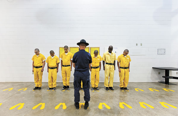 Courtesy Ronald Feldman Fine Arts, New York   Richard Ross: “Orientation Training Phase, Youth Offender System, Pueblo, Colorado, 1” (2010, Digital Inkjet Print, 24”x38”). Orientation Training Phase (OTP), part of the Youth Offender System (YOS) Facility in Pueblo, Colorado. OTP performs intake and assessment of convicted kids and is set up to run like a boot camp, with staff yelling at kids all the time. All of the kids at OTP have juvenile sentences with adult sentences hanging, meaning that if they mess up, they will have to serve their adult sentence. For example, a juvenile could be the reserving a two-year juvenile sentence with 15 years hanging. See page 24.