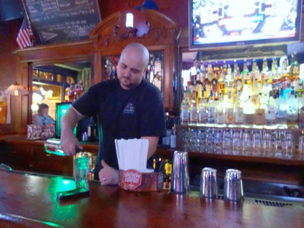 Brendan Kirkpatrick, head bartender at The Village Tavern, poured a drink next to a patron’s phone left carelessly on the bar top. Photo by Paul Bufano