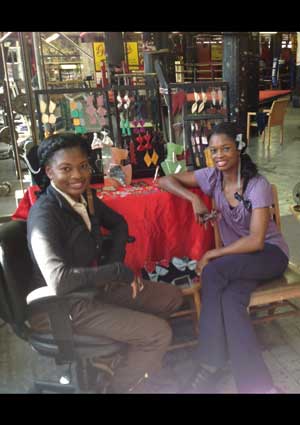 Photo courtesy of the artists Twin sisters Teisher (left) and Keisher, at Gleason’s, in front of items from their line of jewelry. 