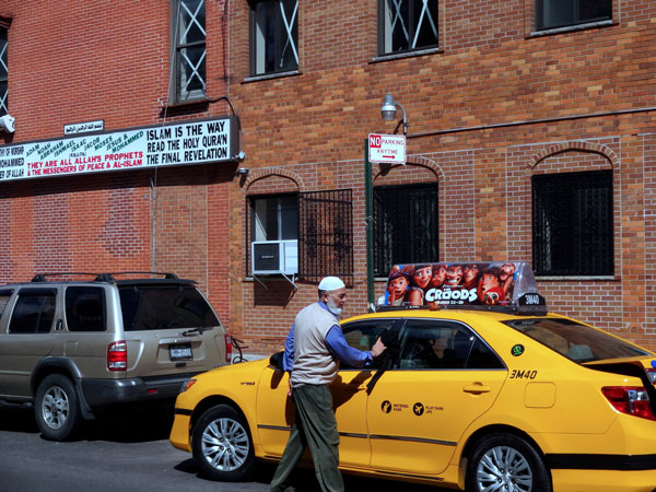 Photo by Paul Bufano Mohammad Sharif cleaned off his cab — parked in a No Parking zone in front of the Madina mosque on First Ave. — as he waited for his food from the halal truck. 