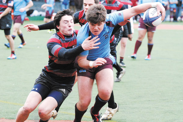 Xavier’s Jimmy Wolfer earning some hard yards while keeping the ball away from a tackling opponent.