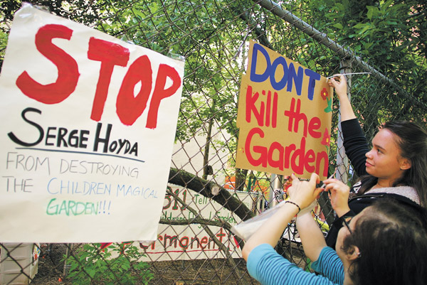 Photo by Sam Spokony Cynthia Marcelino, 17, and Dalia Rodriguez, 18, put up signs on May 20 to protest develop Serge Hoyda’s actions on land used by the Children’s Magical Garden. Both are high school students who attend classes across the street from the garden, and Rodriguez is one of the garden’s youth leaders. Someone later tore down the signs, and Hoyda’s workers are suspected. 