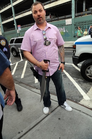 A plainclothes officer from the Fifth Precinct holding a 16-inch sword that allegedly had been carried by Morgan Soto.