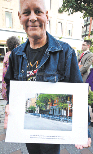 Photo by Tequila Minsky At Wednesday’s announcement of the lawsuit against the Petrosino bike-share station, a resident held up a composite image showing where protesters think the Citi Bike docks should be relocated — into the street, at the northeast corner of Lafayette and Spring Sts.