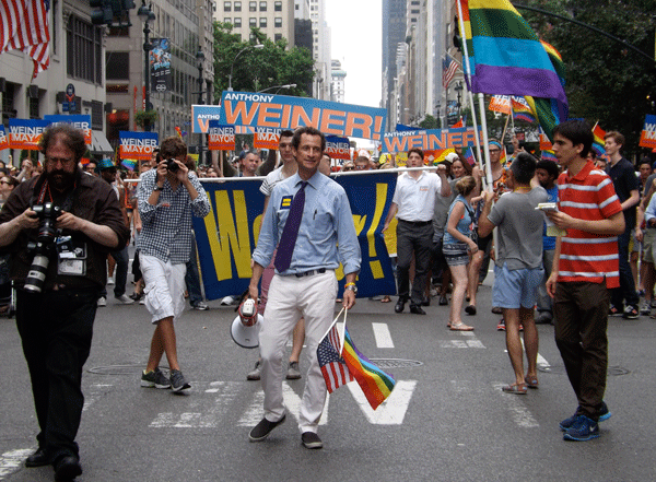 Photo by Gay City News Anthony Weiner sported American and rainbow flags, an HRC badge and — to the media’s disappointment — white pants in the Gay Pride March in Manhattan this June.
