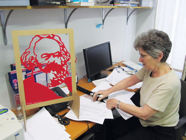 Liz Mestres, Brecht Forum’s outgoing executive director, working in her office at 451 West St. under the watchful gaze of Karl Marx.