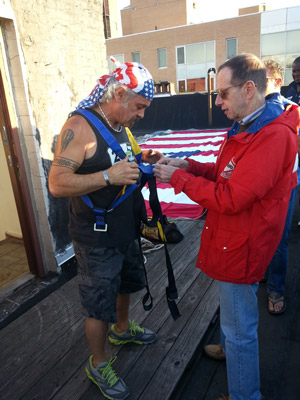Photos by Heather Dubin John Casalinuovo put on a harness to prepare to drop the 1,800-square-foot flag over the building’s side.