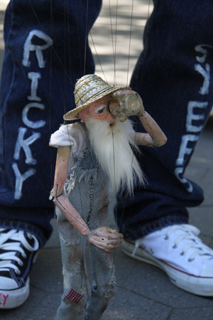 Photos by Tequila Minsky Top, Little Doris feeds a peanut to a squirrel in Washington Square Park. Meanwhile, above, Stix takes a swig of his moonshine — O.K., so he hit himself in the eye, he’s a marionette — and then rummages around in a trash can.