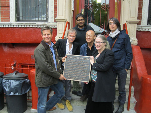 Mascot Flats tenants accepted a plaque on Oct. 10 from Habitat for Humanity commemorating the renovation project 30 years ago. At right in front row is Ann Rupel and at right in the middle row is Don Kao, both original homesteaders from when the building was renovated by Habitat for Humanity in 1984.