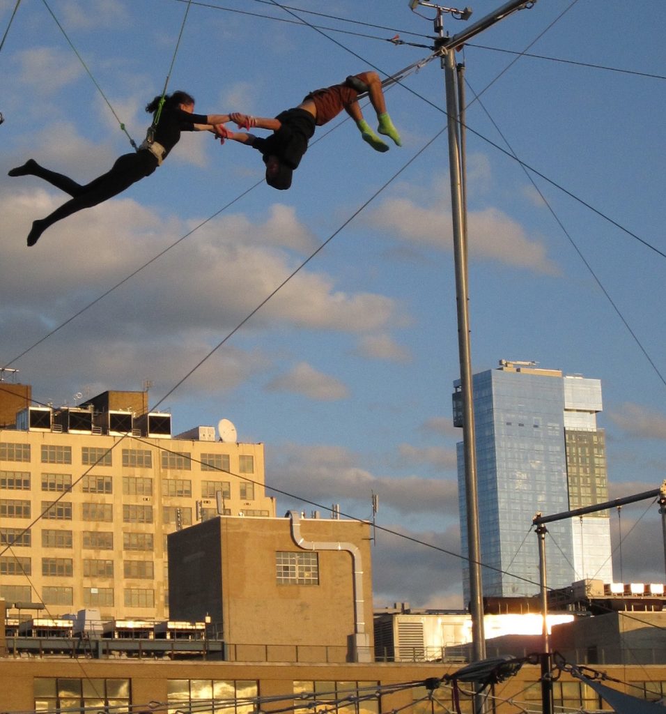 Amid all the buzz about air-rights transfers from Hudson River Park, a couple of swingers at the New York Trapeze School on Pier 40’s rooftop caught some serious air last Sunday afternoon. Behind them, across West St., is the St. John’s Center building, which could receive unused air rights from Pier 40 under legislation awaiting Governor Cuomo’s signature. At right is the Trump Soho Condo Hotel. By one estimation, Hudson River Park currently has enough unused air rights for five  Trump Soho's.  Photo by Lincoln Anderson