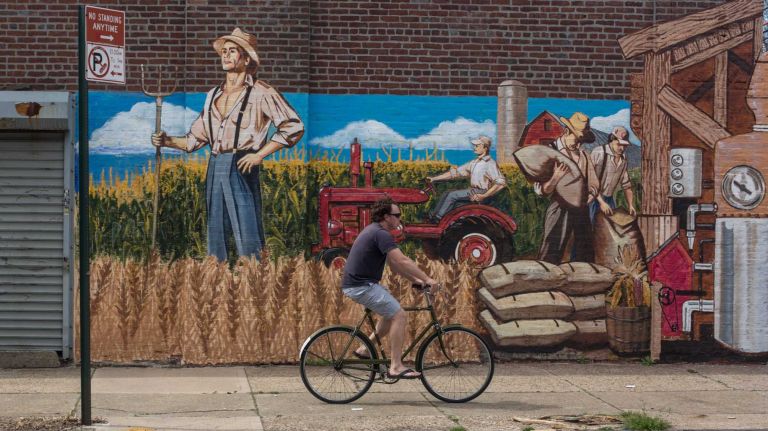 A man rides a bike past a mural painted for Widow Jane Whiskey, a local distillery, on Conover Street in Red Hook. (Apr. 20, 2013)