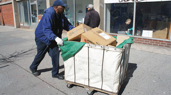A postal worker moved equipment along E. 14th St. to the new post office location last week.     Photo by Liza Béar