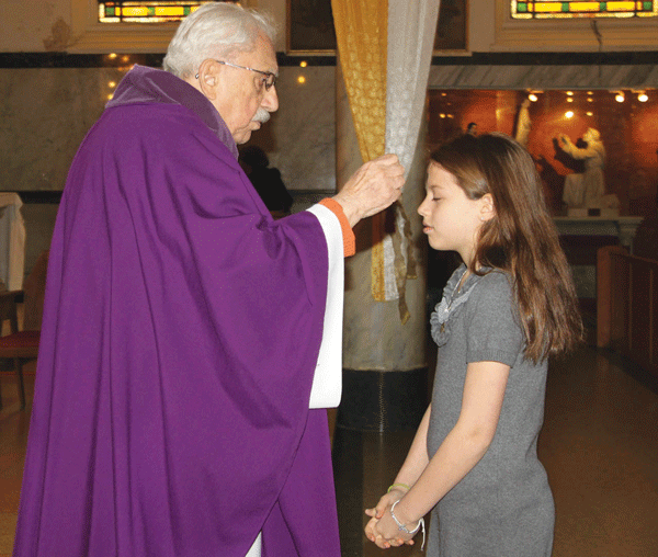 Father Fabian daubs ashes on a worshiper’s forehead on Ash Wednesday.