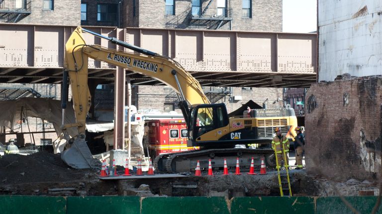 Excavation crews work behind a boarded wall at the site of last week's building collapse in East Harlem on Tuesday, March 18, 2014. 