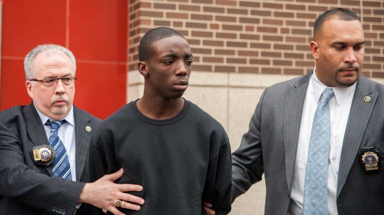 Marcell Dockery, 16, is walked by two police officers from the 60th Precinct on West 8th Street in Brooklyn after he was arrested for his alleged involvement with a fire that resulted in critical injuries to two NYPD Officers. (April 7, 2014)