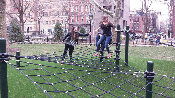 Olivia Markel, left, gave a hand to her sister Anneke on the new cable-rope play structure as dad, Clayton, behind them, waited his turn to try his balancing skill.  Photo by Lincoln Anderson