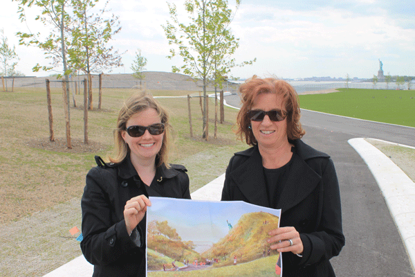 Elizabeth Rapuano, left, the Trust for Governors Island’s chief of staff with Leslie Koch, Trust president. They’re holding an artist’s rendering of the scene in back of them.  Downtown Express photos by Zach Williams 