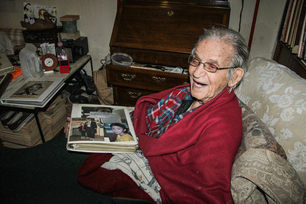 Irwin Corey with a photo binder of family members in his Sniffen Court residence.  Photo by Tequila Minsky