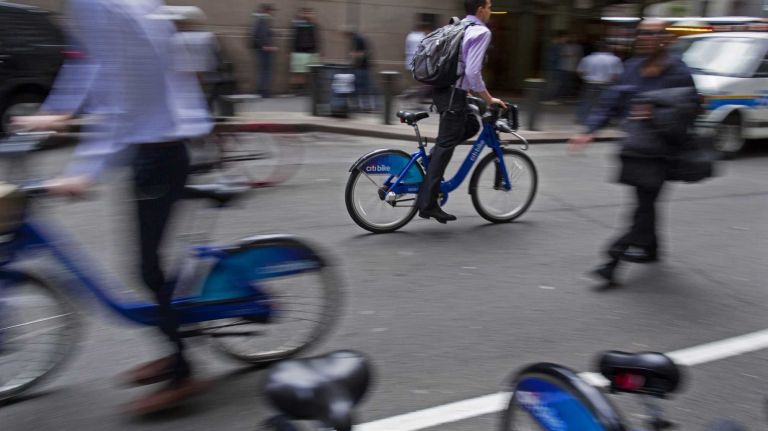 Citi Bikes riders pass by a Citi Bike dock on Vanderbilt Ave. near Grand Central Terminal Friday, May 23, 2104. It will soon be the one year anniversary of Citi Bike coming to New York.