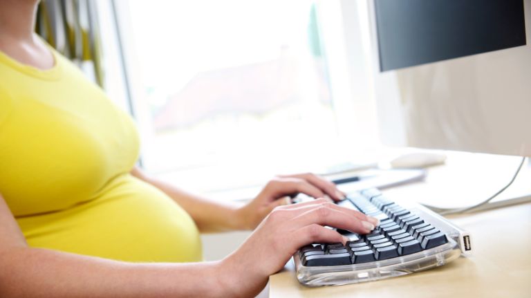 A pregnant woman at a computer.