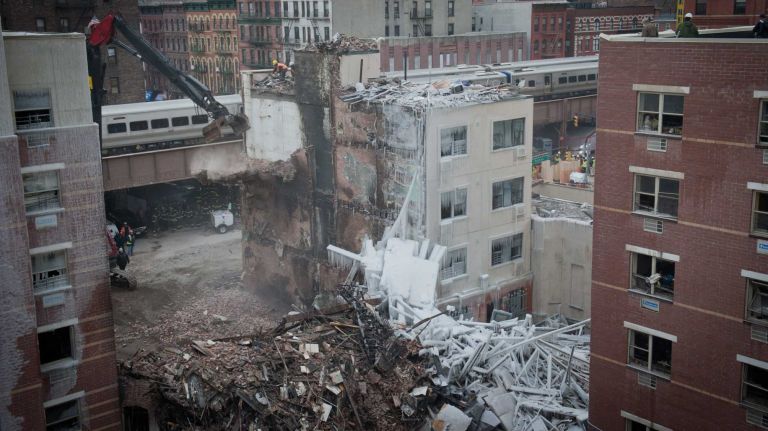 Workers use a crane to clear the site of the East Harlem building explosion on March 12, 2014.