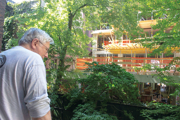 Photos by Zach Williams Pestered to the point of no pesto: W. 15th St. resident Bill Butos observes the garden impacted by early morning construction on a 12-story resident building adjacent to his backyard. 
