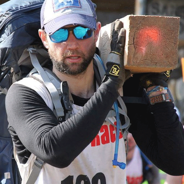 Brian Hennessy, here toting a heavy pack, plus a wood beam, regularly competes in and trains for grueling endurance competitions.