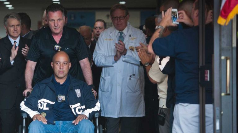 Det. Joseph Trovato pushes the wheelchair of his partner, injured Det. Mario Muniz, at Bellevue Hospital Center on July 30, 2014.