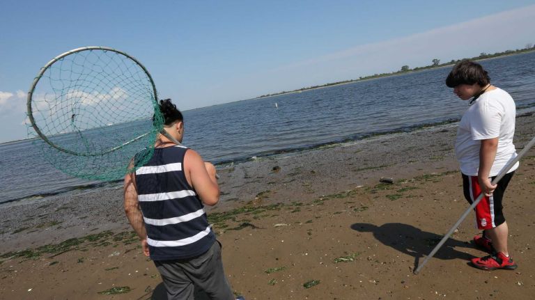 Fernando Rivera, left, and Rubin Rodriguez, from Bushwick, search for crabs along the shore near the Canarsie Pier in Canarsie, Brooklyn, Friday July 11, 2014.