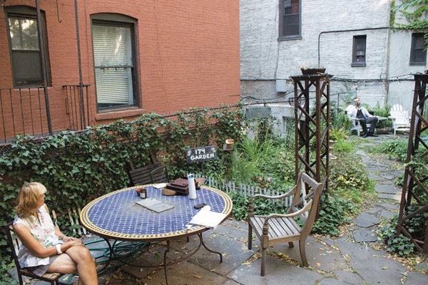 The backyard garden, created by tenants, at 170-174 E. Second St. At left is Mary Ann Siwek and at right is fellow tenant Mark Fritsche. The buildings’ new owner previously tried to demolish the garden, and plans are on file to expand the buildings into the open space.  Photo by Zach Williams