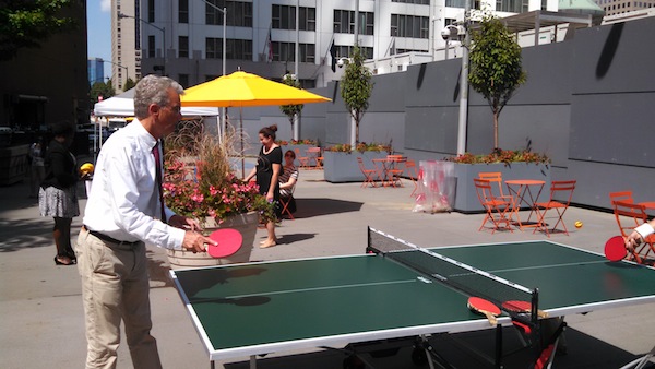 Downtown Express photo by Josh Rogers. David Emil, president of the Lower Manhattan Development Corp., played Ping Pong last Tuesday at the opening of a new temporary plaza and greenmarket at the 5 World Trade Center site. The greenmarket will be open every Tuesday for at least a year on Greenwich St. near Albany St.  