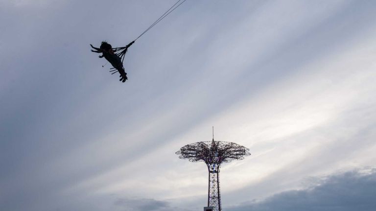 People soar above the boardwalk on the Boardwalk Flight ride in Coney Island Brooklyn, on August 1, 2014. By Anthony Lanzilote.