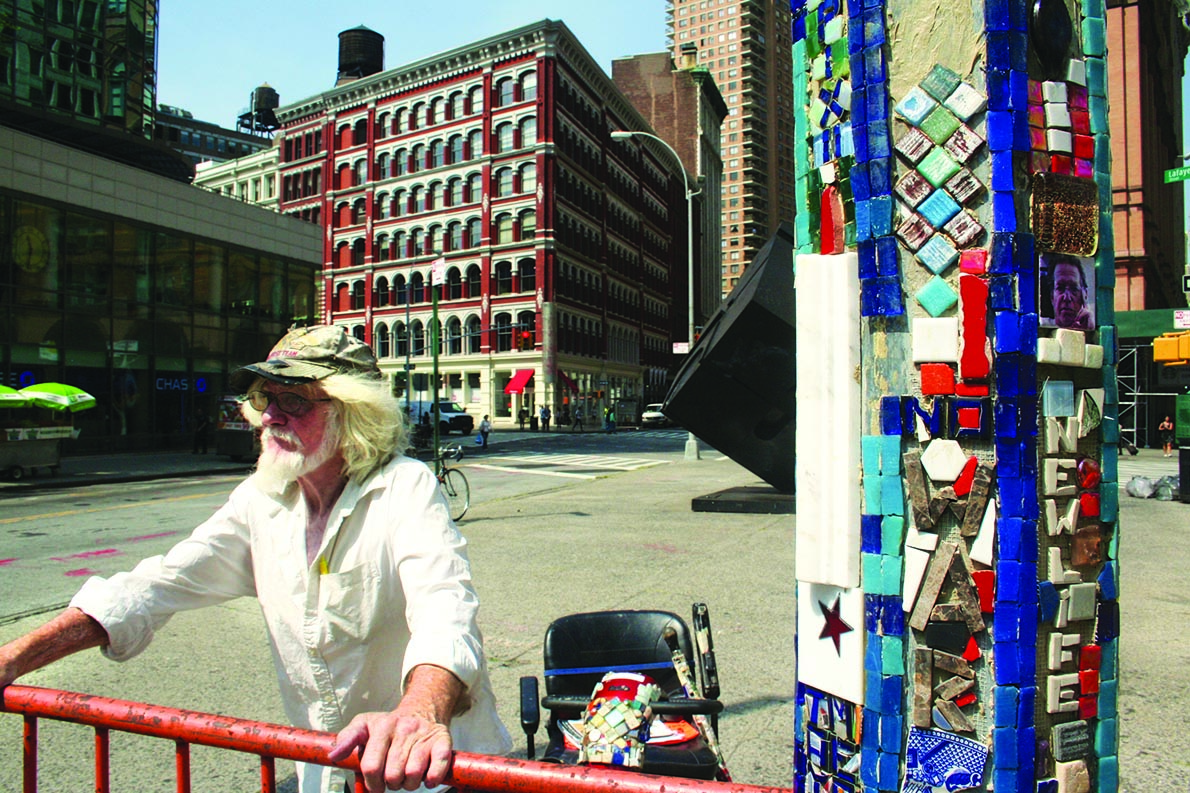 Jim Power stands sentinel over his “Mosaic Trail” lampposts at Astor Place. Parked in the background is his tile-encrusted “Mosaic-mobile.”  Photo by Yannic Rack