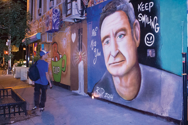 Carlos Pastrana looking at Chico’s mural of Robin Williams on E. 13th St.  Photo by Zach Williams