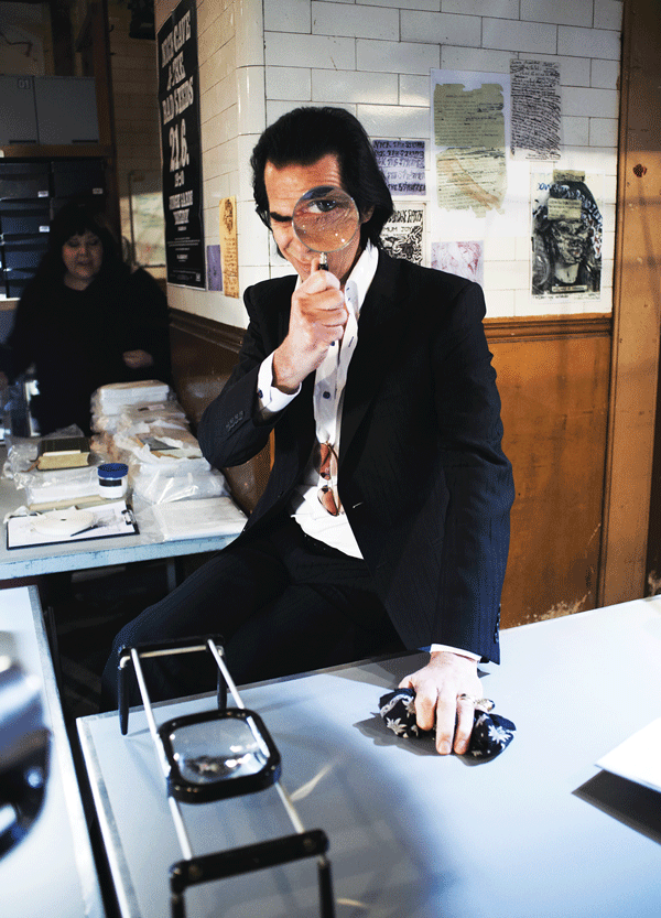 Nick Cave plays with a magnifying glass at his archives.   Courtesy of Drafthouse Films