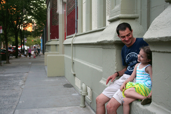 Todd Ferrara and his daughter, Julia, who attends the East Village Community School, in the former P.S. 61 building, sit in front of the school, which is now graffiti-free.