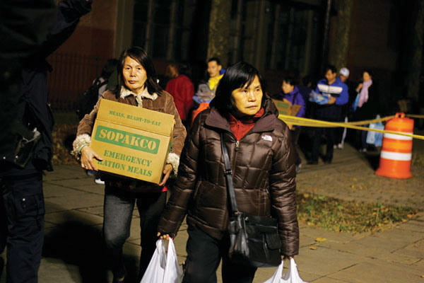 Downtown Express file photo by Sam Spokony Smith Houses residents carrying supplies delivered by the National Guard after Hurricane Sandy hit in 2012.