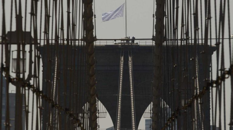 Members of the NYPD's Emergency Service Unit remove a white flag from the  eastern stone support of the Brooklyn Bridge on Tuesday, July 22, 2014.