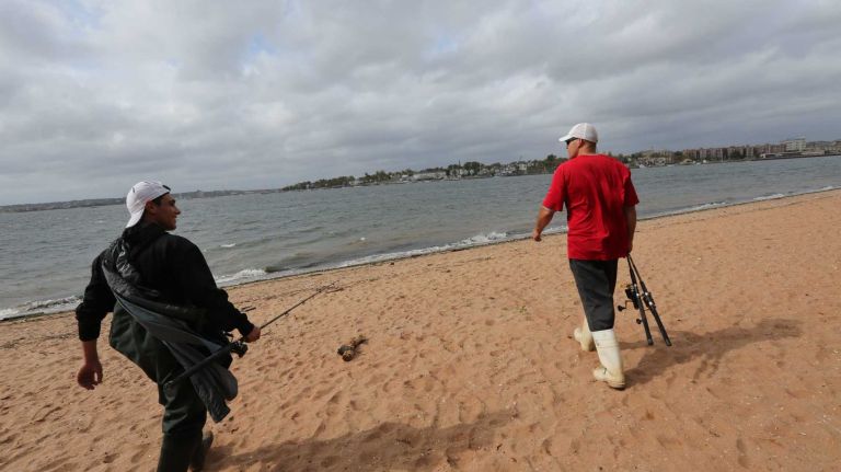 Mike Amen and Joe Ivanoc head out with their fishing rods along the beach at Conference House Park in Tottenville.