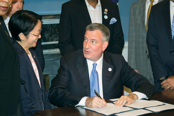 Mayor de Blasio approving a bill — co-sponsored by Councilmember Margaret Chin, left — to boost fines for tenant harassment   Photo by Zach Williams
