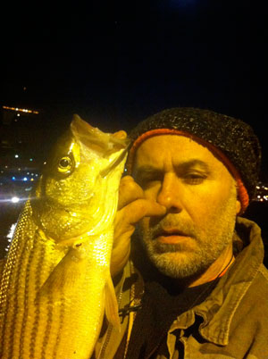Andrew Castrucci with a keeper striped bass that he caught in the East River.