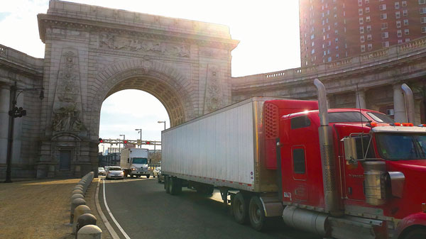 Traffic, including a five-axle tractor-trailer and other trucks, streams off the toll-free Manhattan Bridge and onto Canal St. Westbound Truckers use the free East River bridges and clog Lower Manhattan rather than the Verrazano Bridge, which carries a steep toll for traffic going to Staten Island. Villager file photo